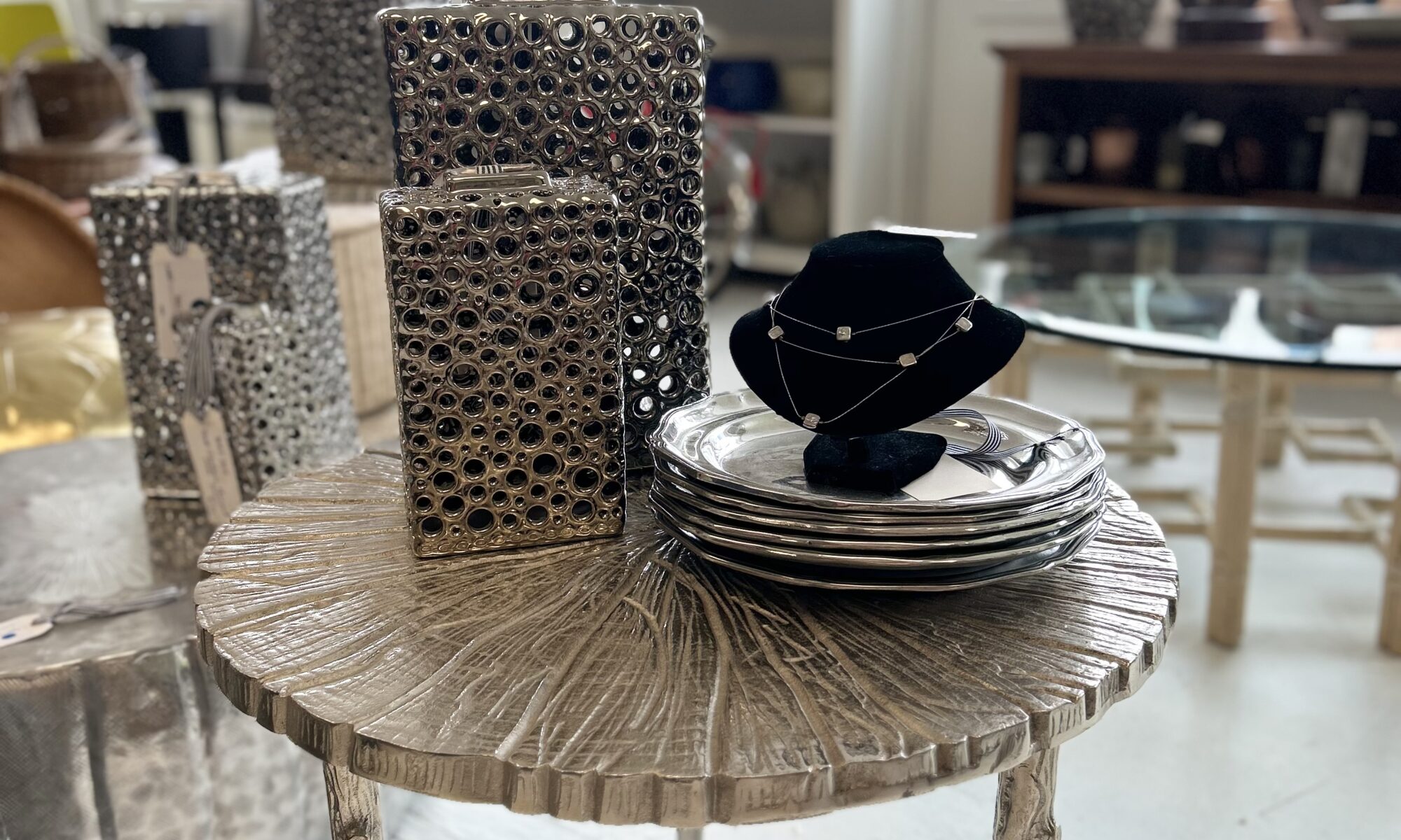 Metallic vases and necklace on wooden table